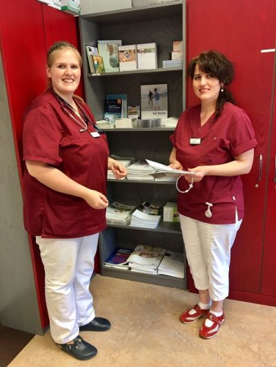 Zwei Kolleginnen vor Schrank mit Infomaterial